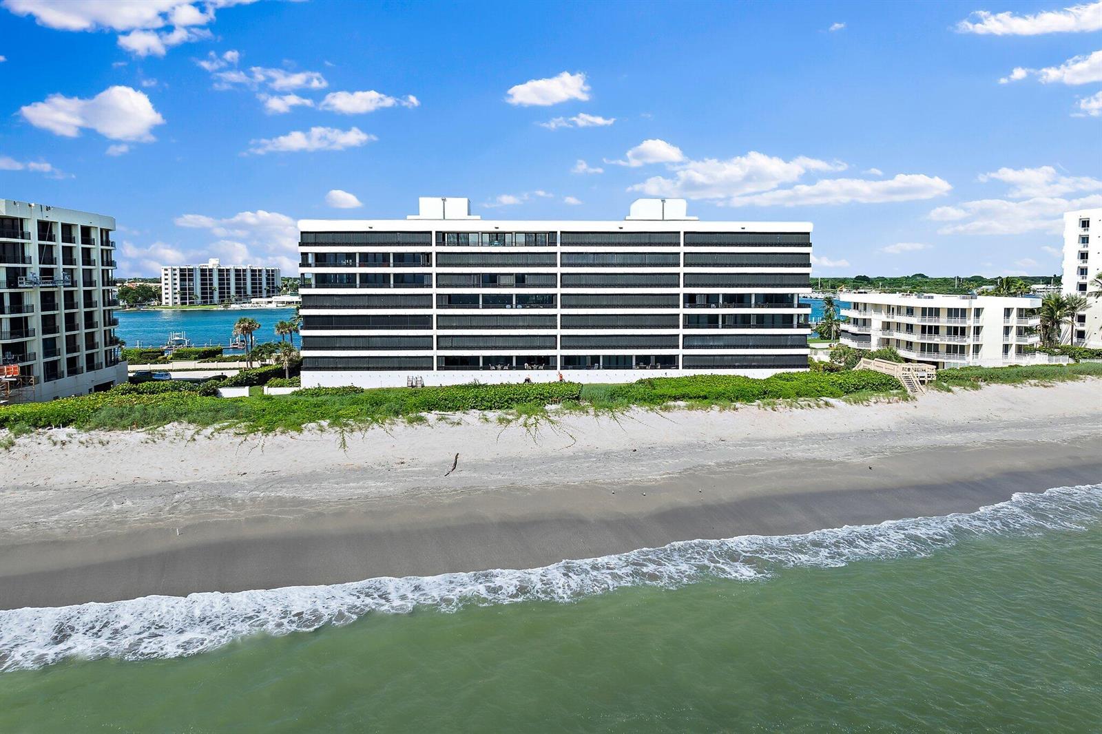 An aerial view of a multi-story beachfront apartment building with a sandy beach and ocean — 19900 Beach Road # 201, Jupiter FL 33469, JUPITER, FL
