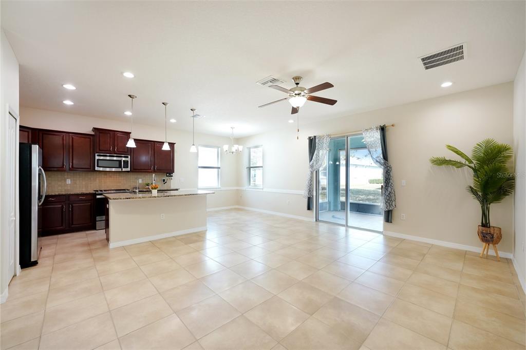 An open-concept kitchen and living area featuring tile floors, dark wood cabinets, and sliding doors — 11129 KISKADEE CIRCLE, NEW PORT RICHEY, FL