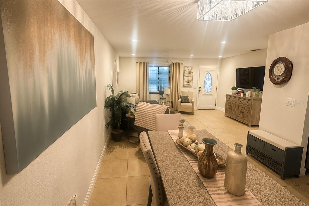 A dining area with a long table leads into a living room with tile flooring — 5120 CHAVES CIRCLE, PORT CHARLOTTE, FL