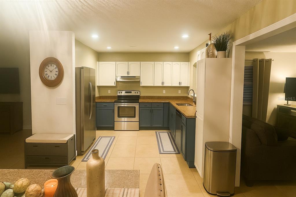 A kitchen features two-toned blue and white cabinetry, stainless steel appliances, and tile flooring — 5120 CHAVES CIRCLE, PORT CHARLOTTE, FL