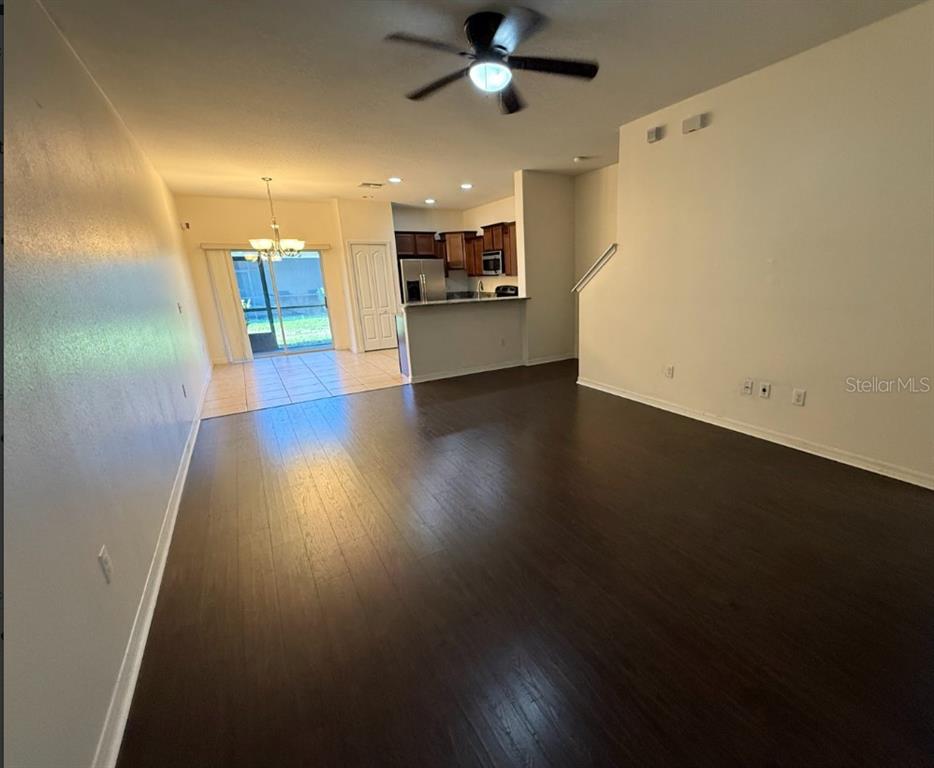 An open-concept living room with dark wood flooring leads to a kitchen and sliding doors — 2807 LANTERN HILL AVENUE, BRANDON, FL