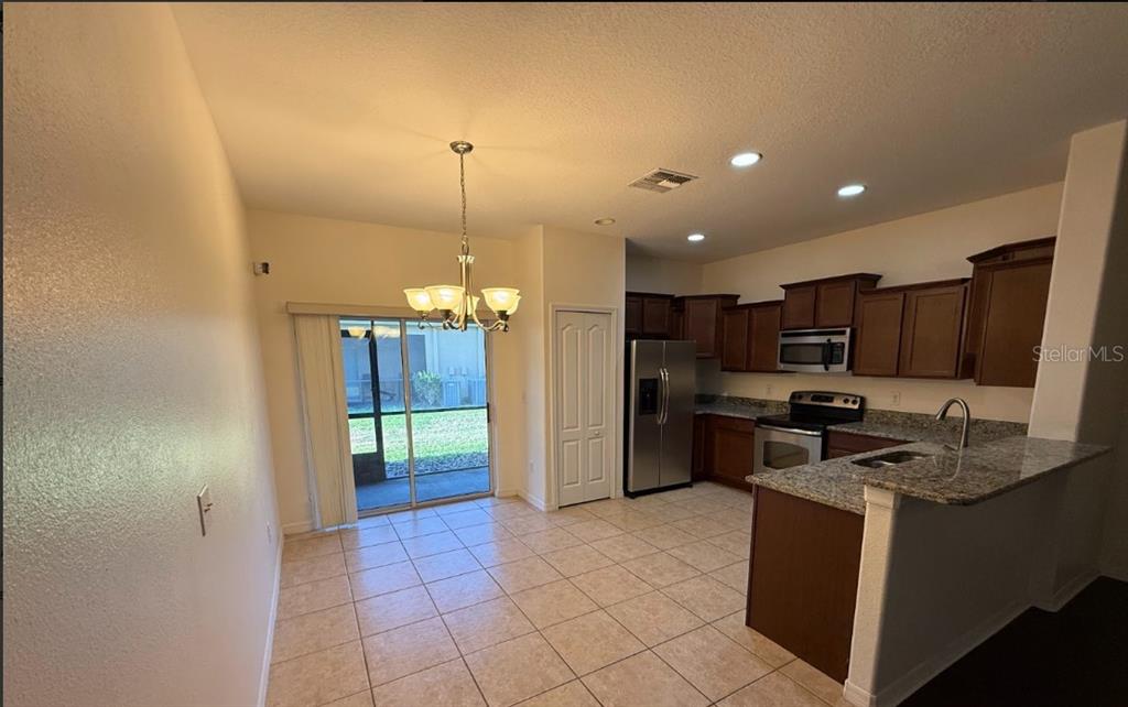 A kitchen and dining area with tile floors, granite countertops, and a sliding glass door — 2807 LANTERN HILL AVENUE, BRANDON, FL