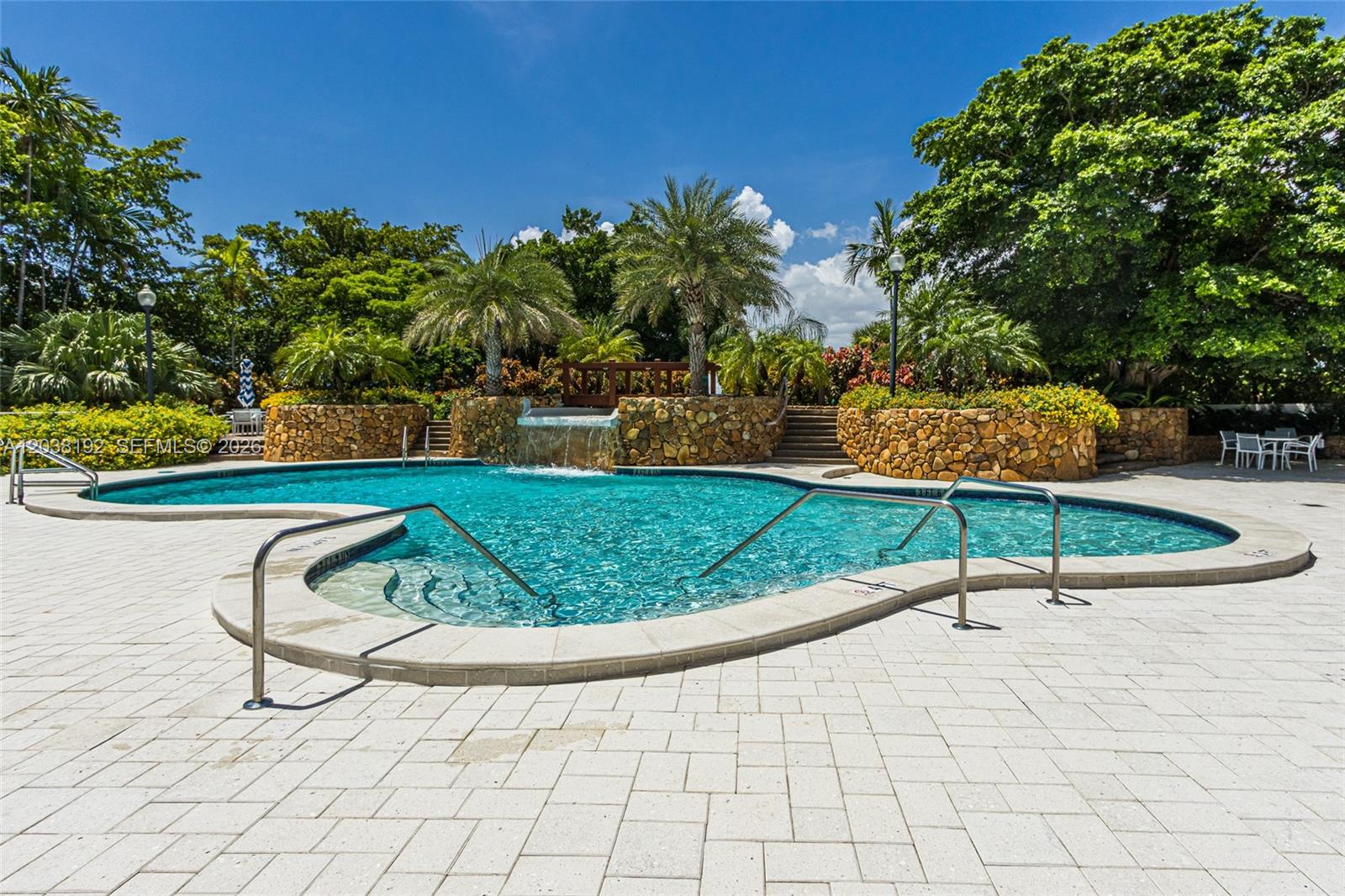 A swimming pool with a stone waterfall feature and palm trees sits on a patio — 4000 Towerside Ter # 1701, Miami FL 33138, MIAMI, FL