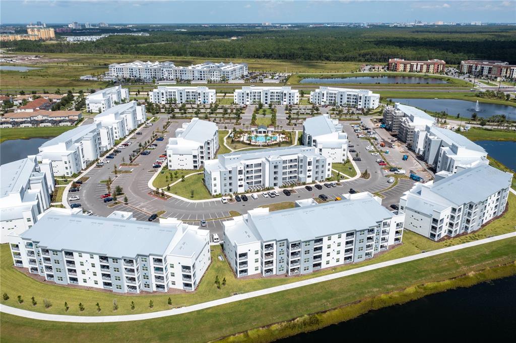 An aerial view shows a large apartment complex with multiple buildings surrounding a central pool — 3161 PARADOX CIRCLE UNIT # 108, KISSIMMEE, FL