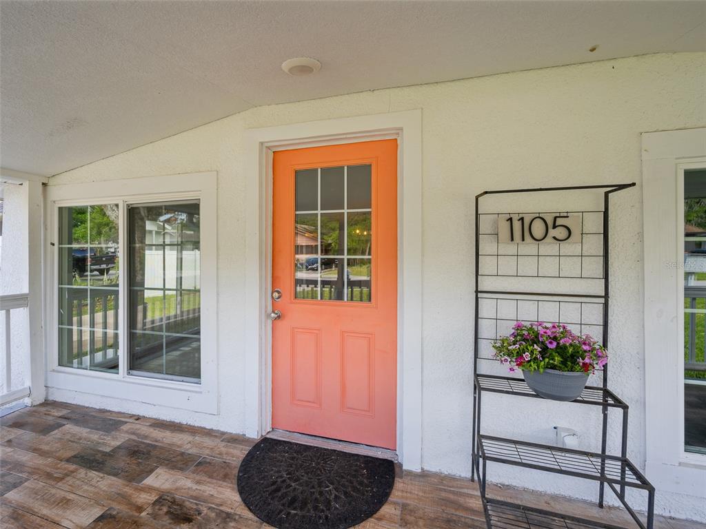 A bright orange front door sits on a porch with wood-look tile flooring — 1105 WILLOW AVENUE, SANFORD, FL