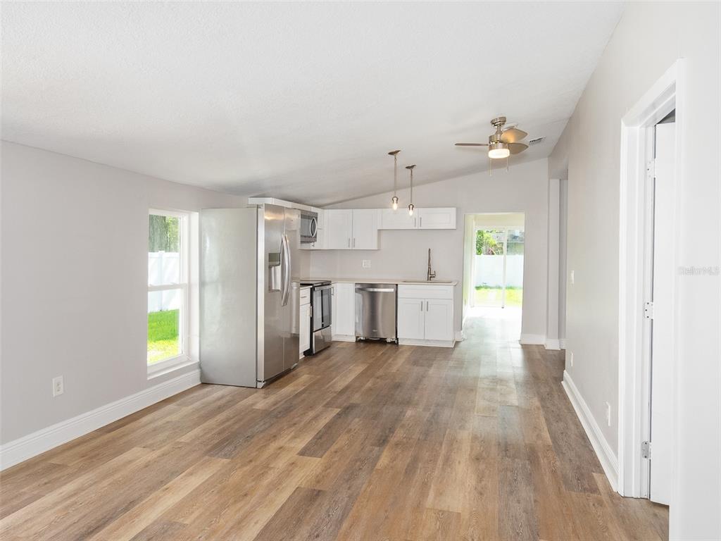 A kitchen with stainless steel appliances, white cabinets, and wood-look flooring in an open room — 1105 WILLOW AVENUE, SANFORD, FL