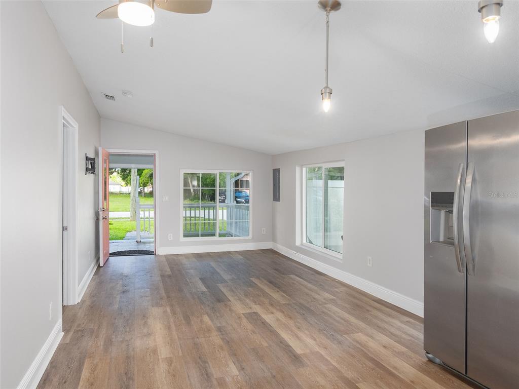 This room features light gray walls, wood-look flooring, a ceiling fan, and a stainless refrigerator — 1105 WILLOW AVENUE, SANFORD, FL