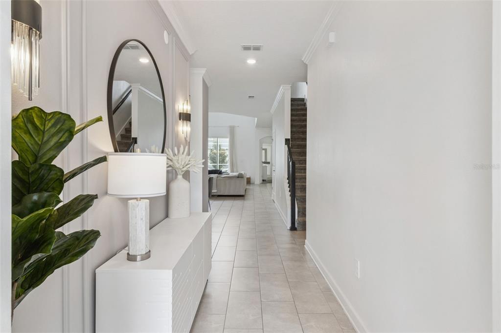 A bright entryway features a white console table, a round mirror, and tile flooring — 9095 SOMMERSET HILLS DRIVE, DAVENPORT, FL