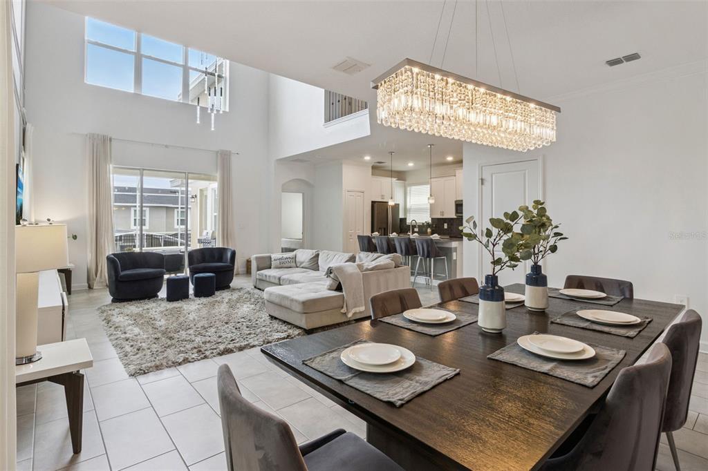 An open-concept living and dining area features high ceilings, a crystal chandelier, and tile flooring — 9095 SOMMERSET HILLS DRIVE, DAVENPORT, FL