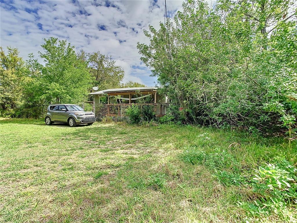 A silver car is parked on a grassy lawn in front of a small house — 1518 27TH STREET SE, RUSKIN, FL