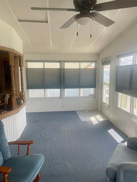 A sunroom features blue carpeting, white paneled walls, a ceiling fan, and large windows — 152 SHADY LANE UNIT 152, PALMETTO, FL