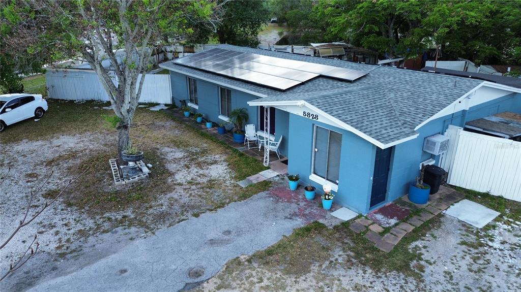 An aerial view shows a blue house with a solar panel array on the roof — 5828 HARCOURT AVENUE, ORLANDO, FL