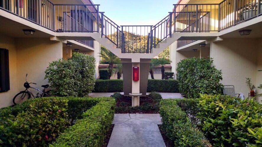An exterior view of an apartment complex courtyard featuring a central staircase and landscaping — 120 N M Street # L, FL 33460, FL