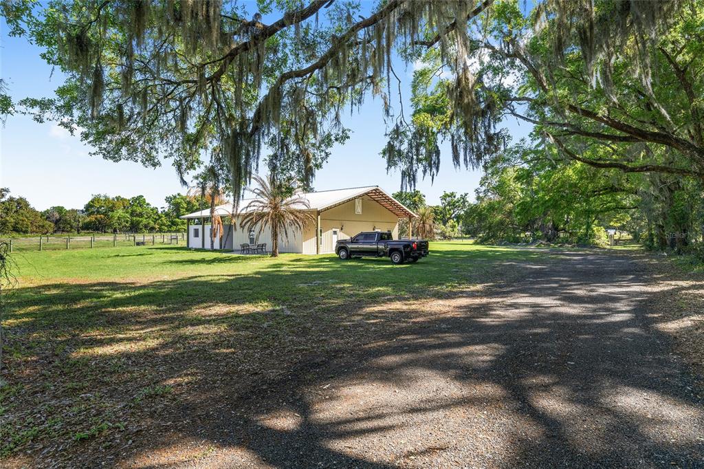 A black pickup truck is parked on a gravel driveway in front of a metal building — 13869 S HWY 475, SUMMERFIELD, FL