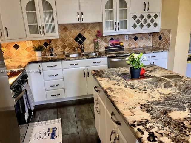 A kitchen features white cabinetry, granite countertops, a tiled backsplash, and a central island — 3910 Inverrary Blvd # B, Lauderhill FL 33319, LAUDERHILL, FL