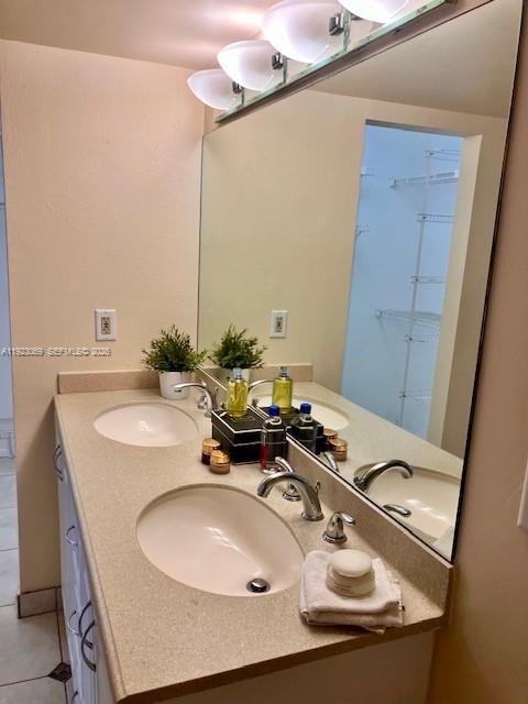 A bathroom vanity features a double sink, beige countertop, large mirror, and overhead lighting — 3910 Inverrary Blvd # B, Lauderhill FL 33319, LAUDERHILL, FL