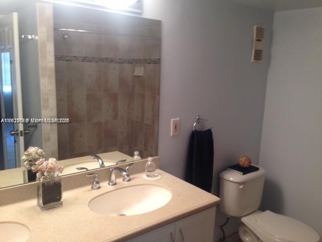 A bathroom features a vanity with a beige countertop, a mirror, and a white toilet — 3910 Inverrary Blvd # B, Lauderhill FL 33319, LAUDERHILL, FL