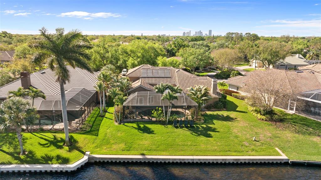An aerial view shows a waterfront house with a screened pool and tile roof — 4731 COCONUT PALM CIRCLE NE, ST PETERSBURG, FL