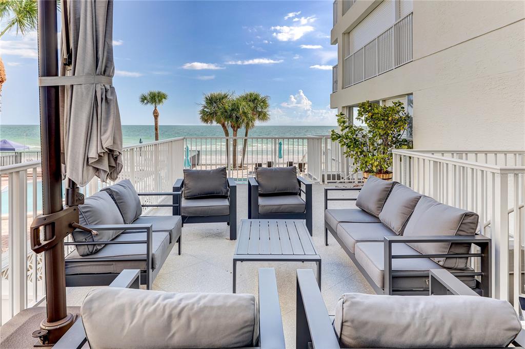 A furnished outdoor patio overlooks the ocean with gray seating and a central coffee table — 16332 GULF BOULEVARD UNIT 1C, REDINGTON BEACH, FL