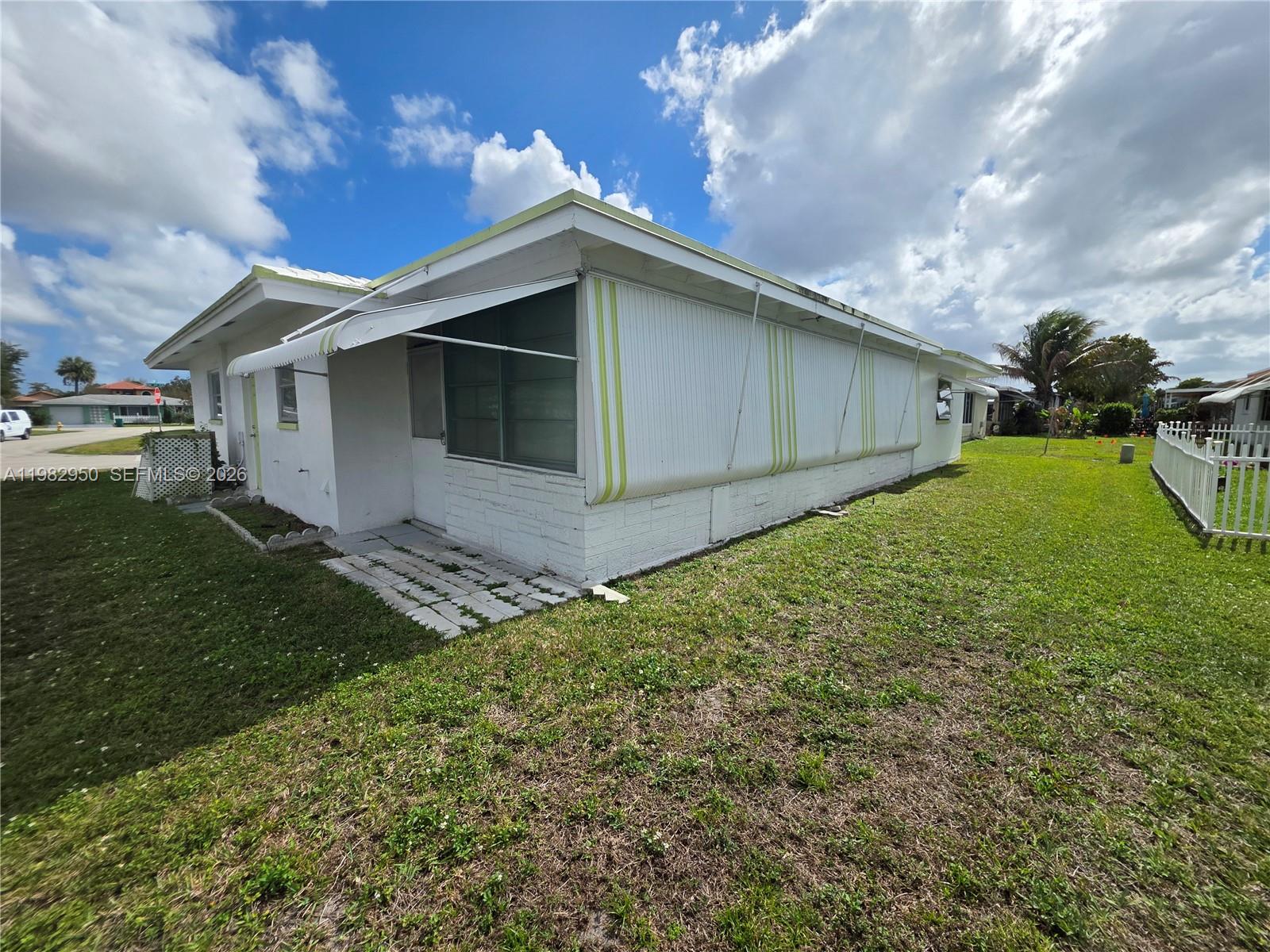 The exterior of a white house features a metal awning over a side window — 5415 NW 49th Ter, Tamarac FL 33319, TAMARAC, FL