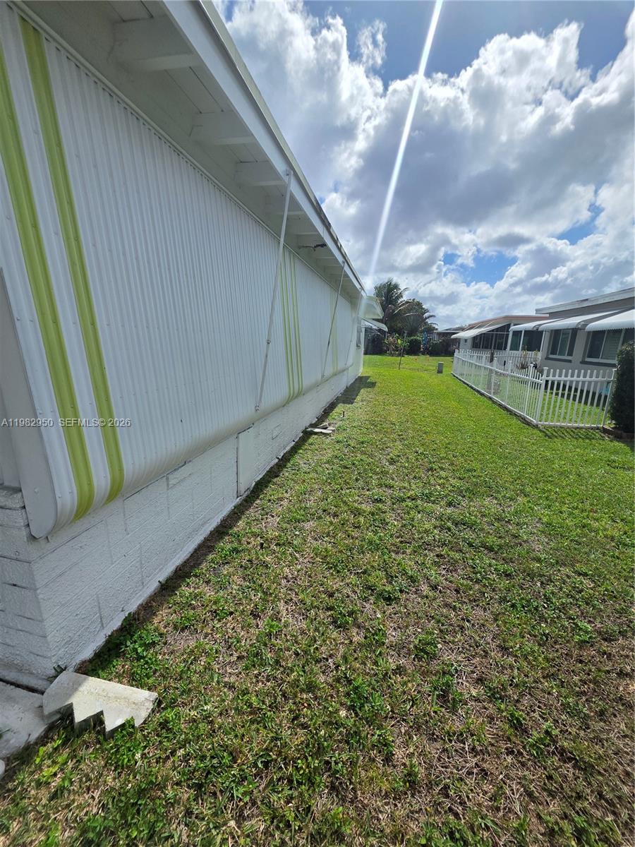 The exterior of a mobile home features white metal siding with green vertical stripes — 5415 NW 49th Ter, Tamarac FL 33319, TAMARAC, FL