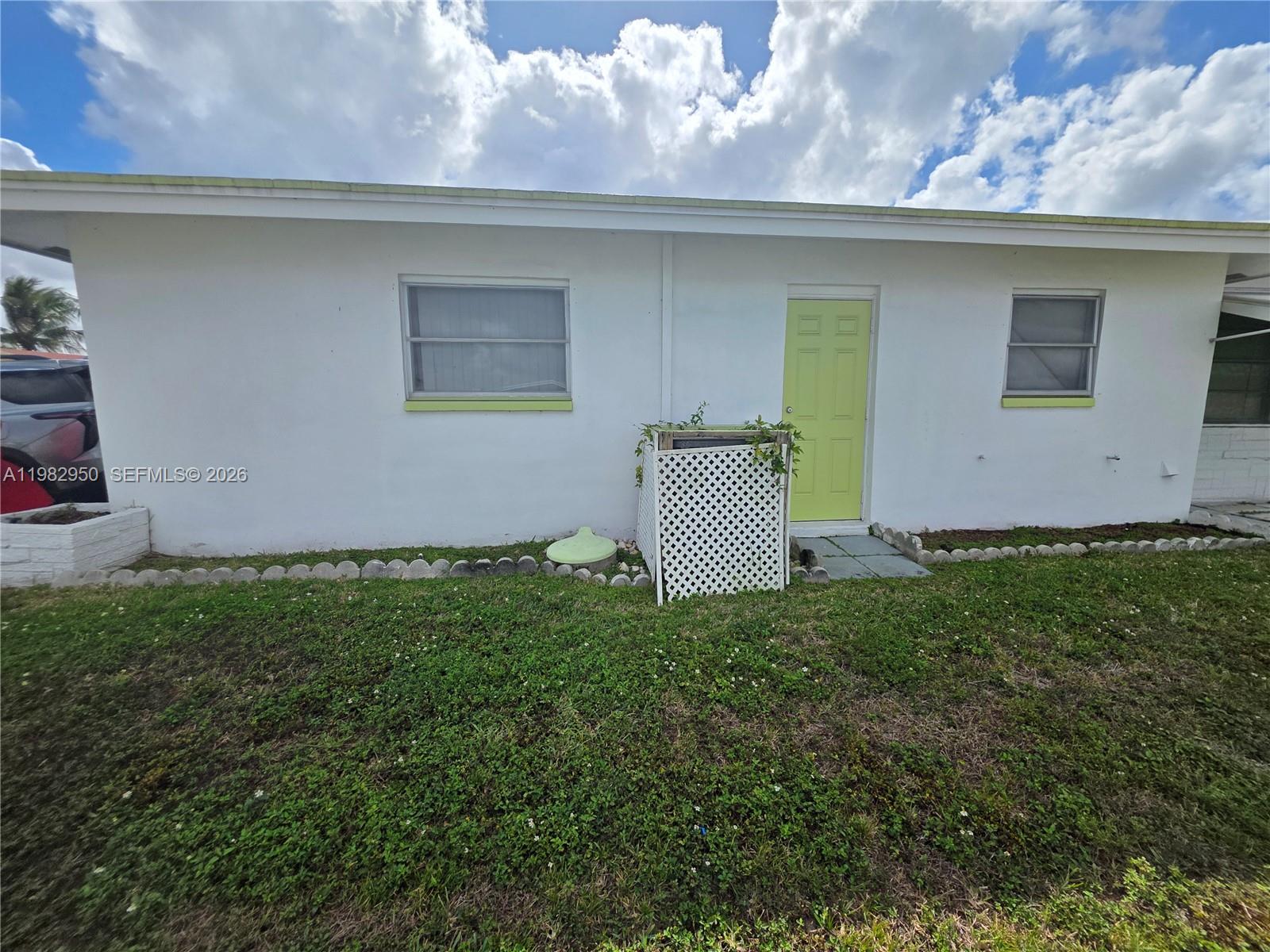 The exterior of a white house features a lime green door and a lattice screen — 5415 NW 49th Ter, Tamarac FL 33319, TAMARAC, FL