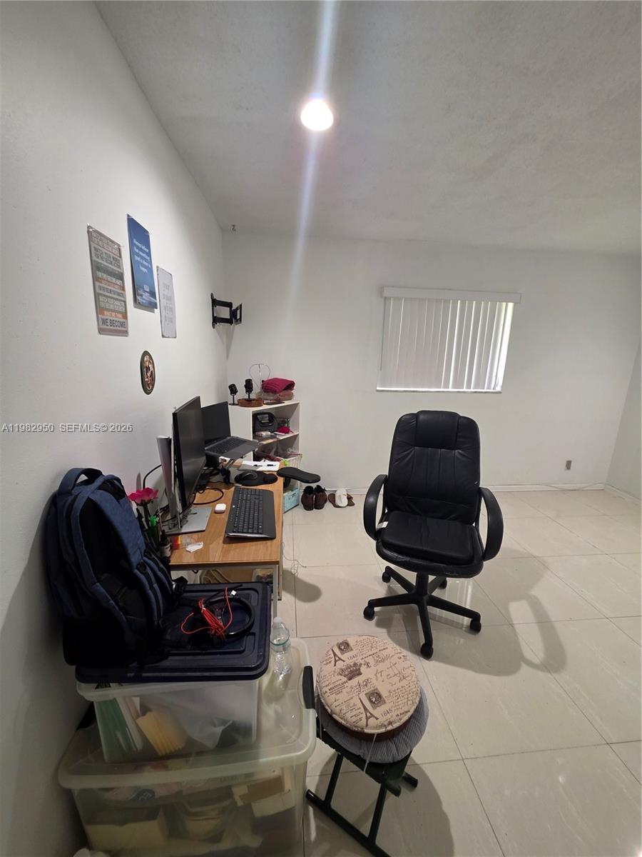 A home office features a desk with computer equipment, a black chair, and tile flooring — 5415 NW 49th Ter, Tamarac FL 33319, TAMARAC, FL