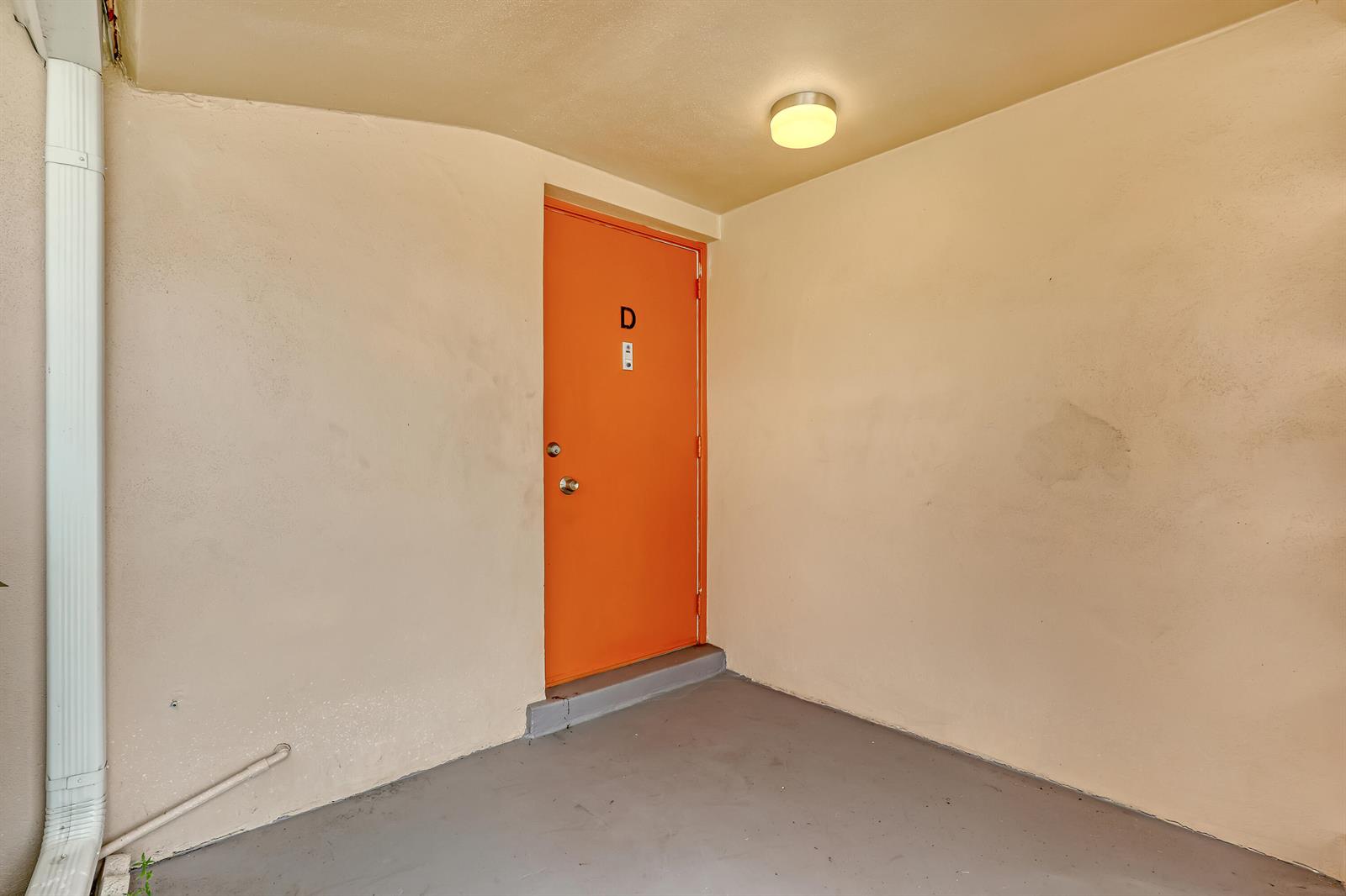 An orange door labeled D is set into a beige stucco wall on a porch — 2747 Dudley Drive E # D, West Palm Beach FL 33415, WEST PALM BEACH, FL