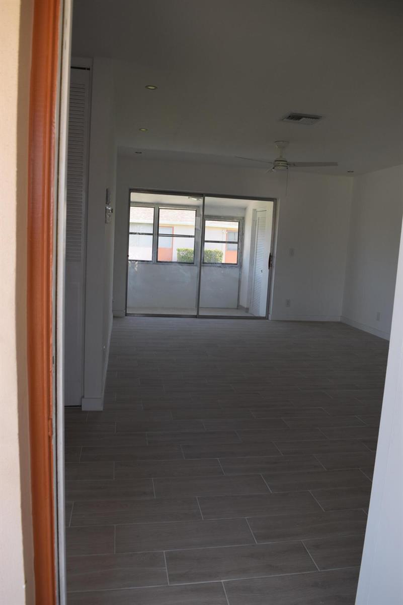 An interior view of a living area with light-colored tile flooring and a sliding glass door — 2747 Dudley Drive E # D, West Palm Beach FL 33415, WEST PALM BEACH, FL