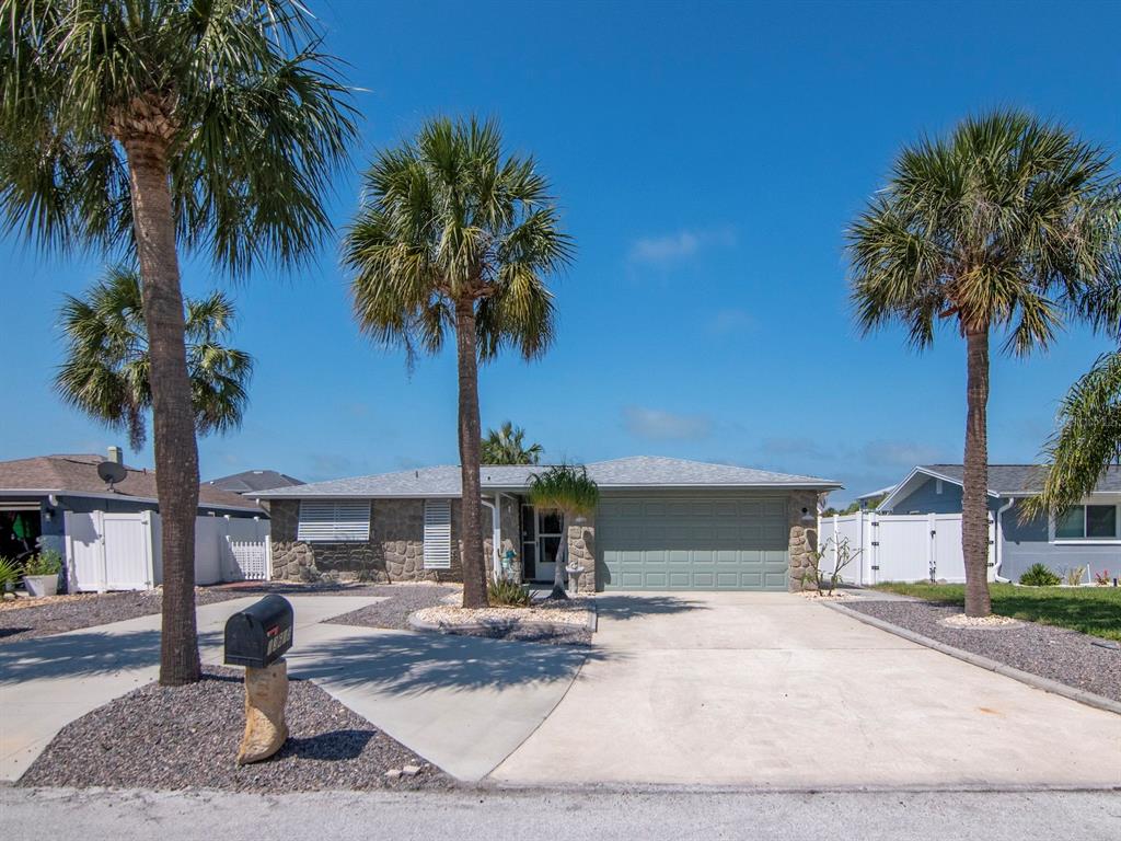 A single-story house with a stone facade, a two-car garage, and three palm trees — 13615 STACEY DRIVE, HUDSON, FL