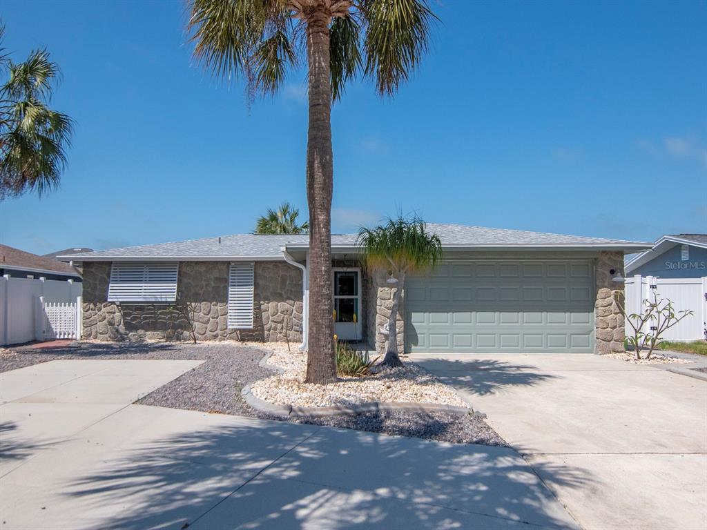 A single-story house with a stone facade, a two-car garage, and a palm tree out front — 13615 STACEY DRIVE, HUDSON, FL