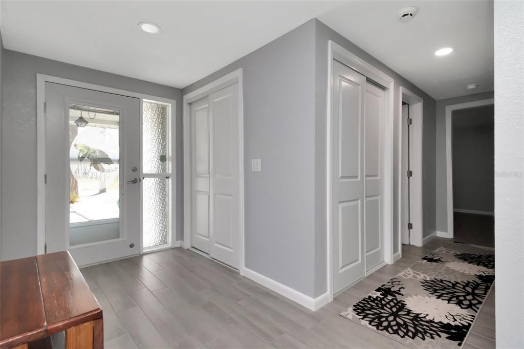 An entryway features gray walls, light wood-look tile flooring, two white closets, and a front door — 13615 STACEY DRIVE, HUDSON, FL
