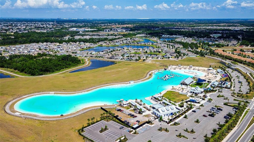 An aerial view of a large, turquoise man-made lagoon surrounded by parking and residential neighborhoods — 5513 LITTLE PATH DRIVE, WIMAUMA, FL
