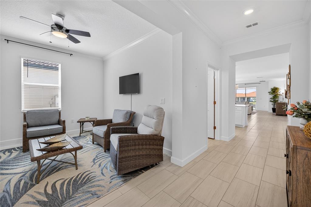 A living area with wicker chairs and a patterned rug leads to an open kitchen — 5513 LITTLE PATH DRIVE, WIMAUMA, FL