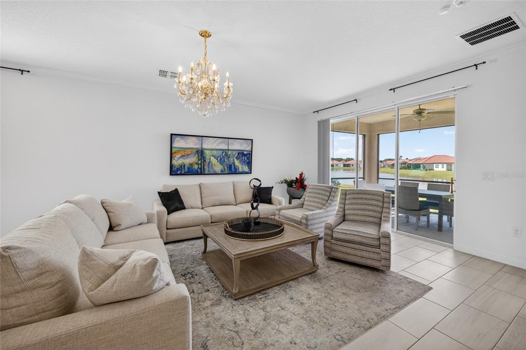 A living room features a beige sofa, two patterned armchairs, a coffee table, and a chandelier — 5513 LITTLE PATH DRIVE, WIMAUMA, FL