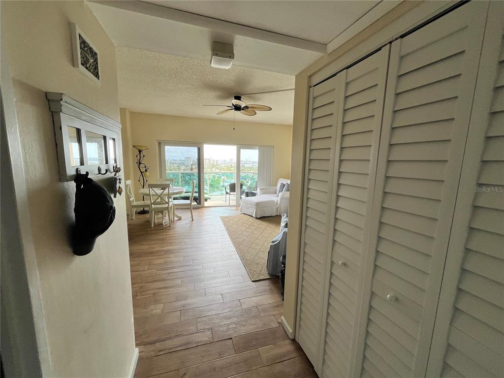 A view from a hallway into a living area with wood-look floors and balcony access — 880 MANDALAY AVENUE UNIT S806, CLEARWATER BEACH, FL