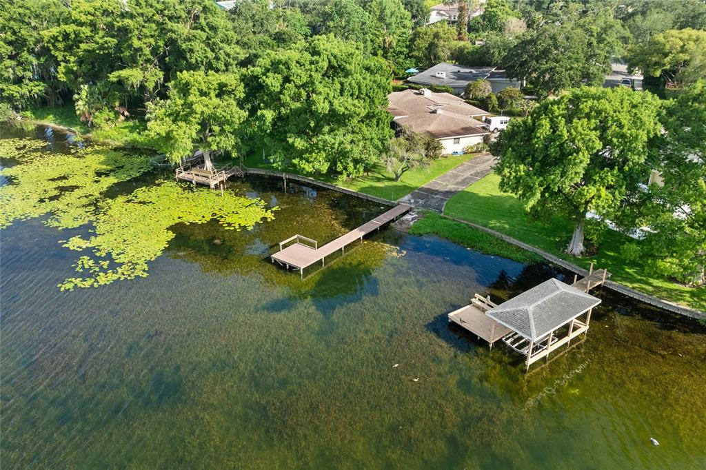 An aerial view shows a house with a dock and boat slip on a lake — 338 BLUE HERON DRIVE, WINTER PARK, FL