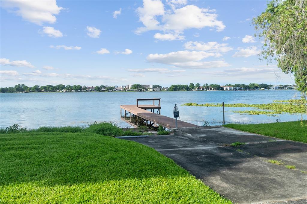 A concrete boat ramp leads to a wooden dock on a lake with lily pads — 338 BLUE HERON DRIVE, WINTER PARK, FL