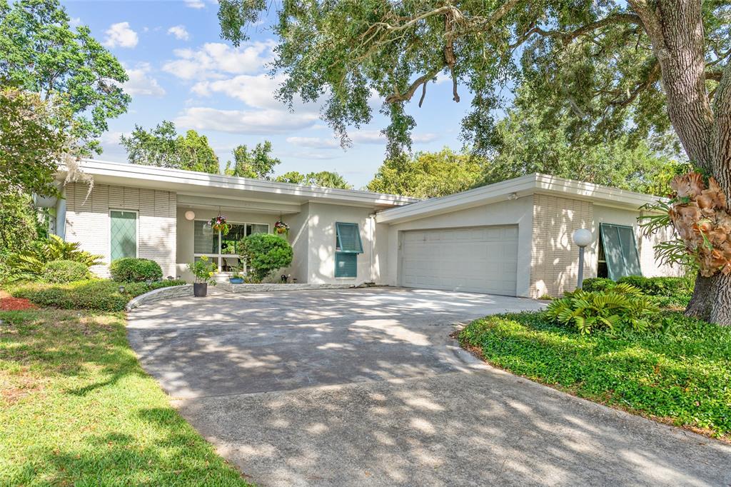 A single-story house with a white brick exterior, a two-car garage, and a concrete driveway — 338 BLUE HERON DRIVE, WINTER PARK, FL