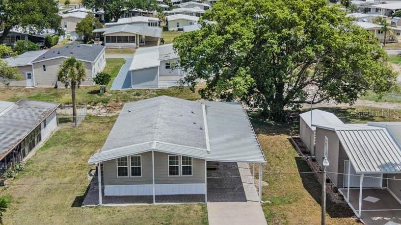 An aerial view shows a single-story manufactured home with a metal carport and driveway — 36747 LAKEWOOD DRIVE, ZEPHYRHILLS, FL