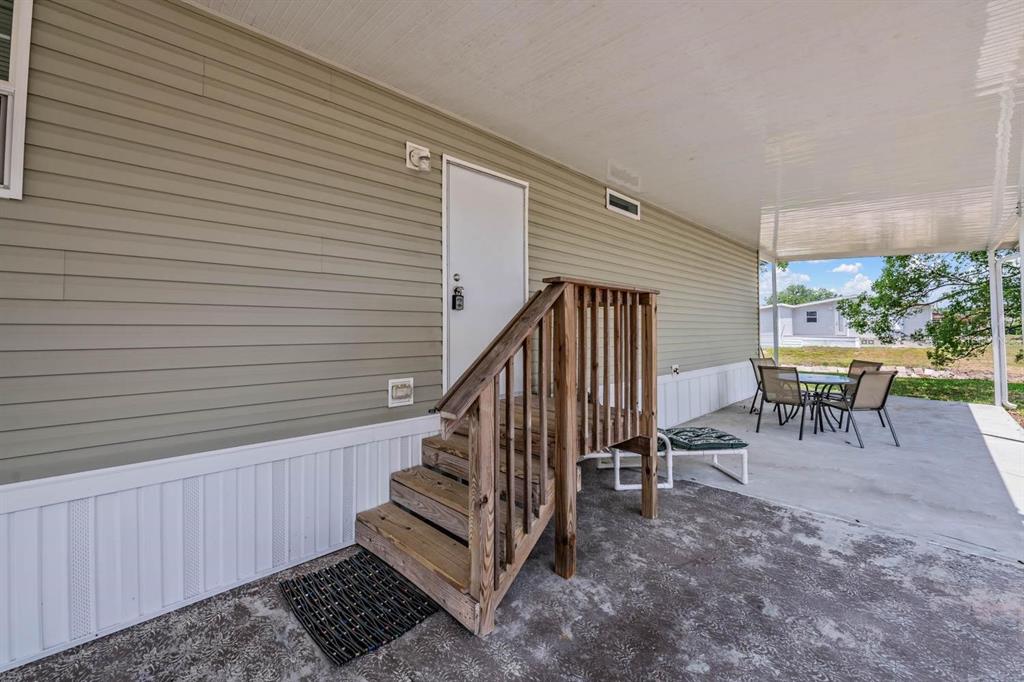 A wooden staircase leads to a white door on the side of a mobile home — 36747 LAKEWOOD DRIVE, ZEPHYRHILLS, FL
