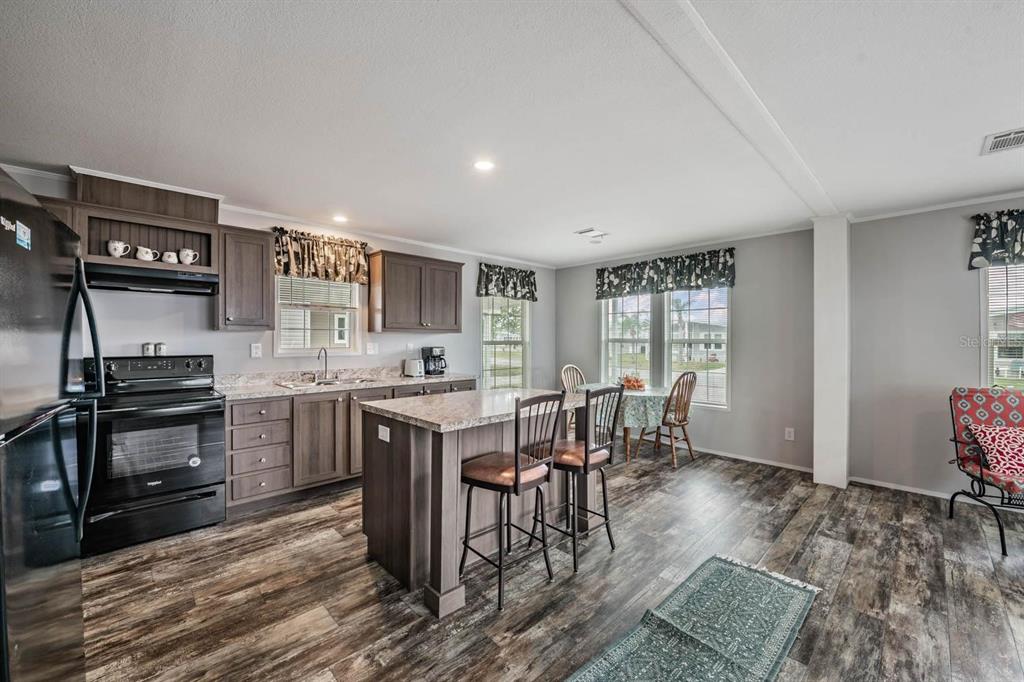 A kitchen with dark wood cabinets, a center island with bar stools, and wood-look flooring — 36747 LAKEWOOD DRIVE, ZEPHYRHILLS, FL