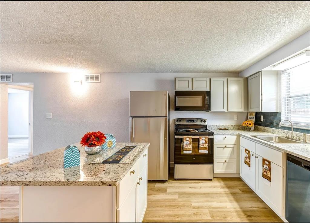 A kitchen with white cabinets, granite countertops, stainless steel appliances, and a central island — 9911 AQUARIUS DRIVE UNIT 4, PORT RICHEY, FL