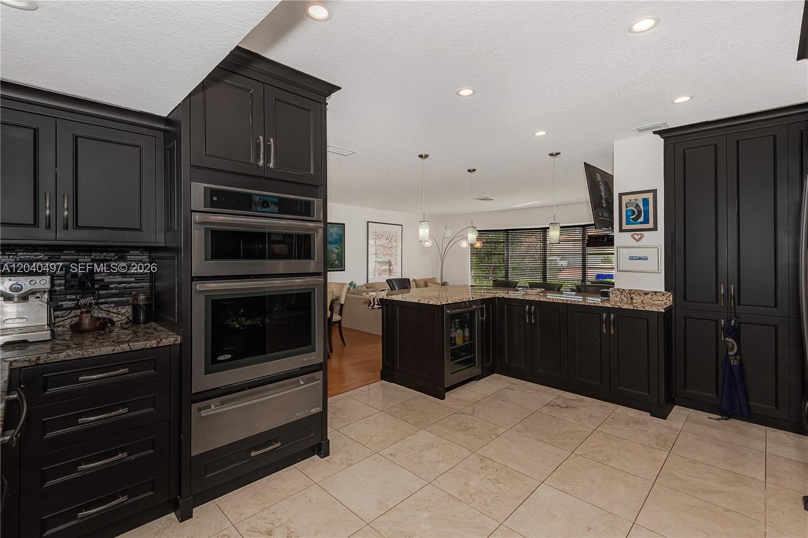 A kitchen features dark cabinetry, stainless steel appliances, granite countertops, and light-colored tile flooring — 3900 N 43rd Ave, Hollywood FL 33021, HOLLYWOOD, FL