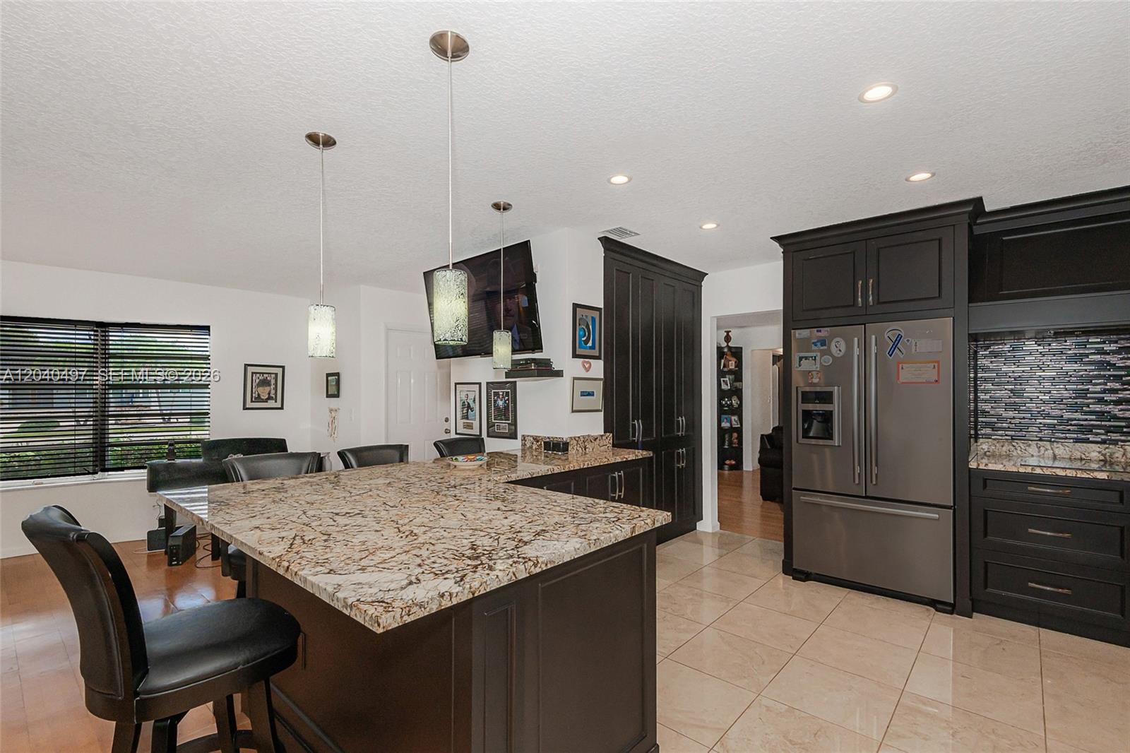 A kitchen features dark cabinetry, a granite-topped island with bar seating, and tile flooring — 3900 N 43rd Ave, Hollywood FL 33021, HOLLYWOOD, FL