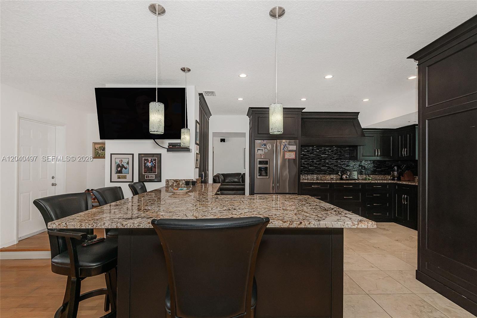 A kitchen features a large granite-topped island, dark cabinetry, and pendant lighting — 3900 N 43rd Ave, Hollywood FL 33021, HOLLYWOOD, FL