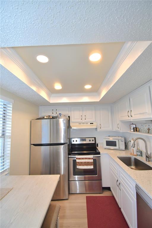 A kitchen features white cabinets, stainless steel appliances, a recessed ceiling, and light-colored countertops — 952 VIRGINIA STREET UNIT 209, DUNEDIN, FL