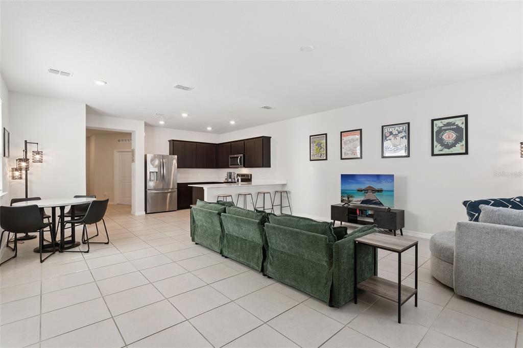 An open-concept living room and kitchen featuring tile flooring, dark cabinetry, and a green sofa — 6926 REVERIE PARK AVENUE, ORLANDO, FL