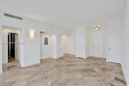 An interior view of a room with white walls, marble flooring, and several closed doors — 90 Edgewater # 18, Coral Gables FL 33133, CORAL GABLES, FL