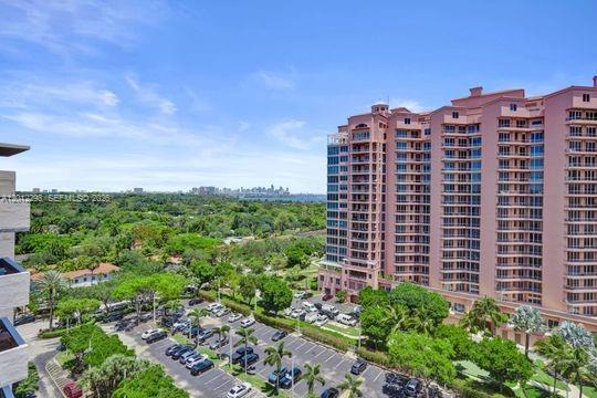 An elevated view shows a large pink apartment building overlooking a parking lot and trees — 90 Edgewater # 18, Coral Gables FL 33133, CORAL GABLES, FL